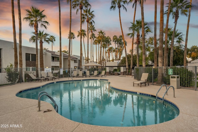 pool at dusk featuring a patio area, a community pool, and fence