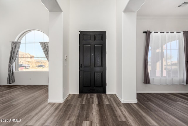 foyer entrance with ornamental molding and dark hardwood / wood-style floors