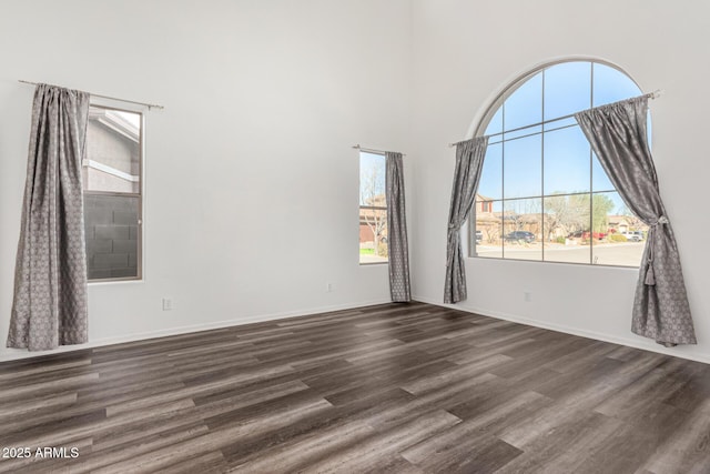 empty room with dark wood-type flooring and a high ceiling