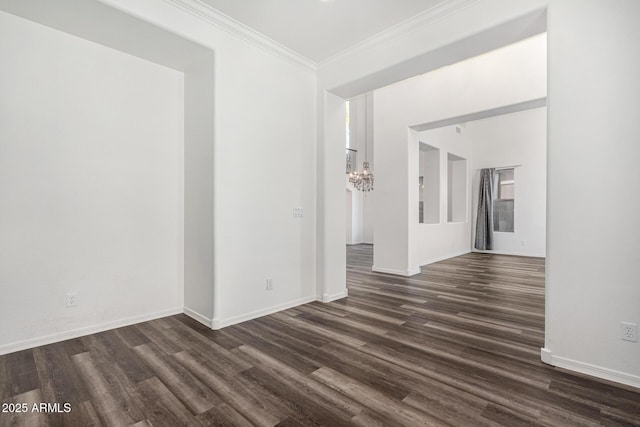 empty room with ornamental molding, a notable chandelier, and dark hardwood / wood-style flooring