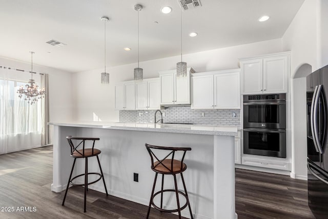 kitchen featuring white cabinetry, hanging light fixtures, a kitchen breakfast bar, and stainless steel double oven