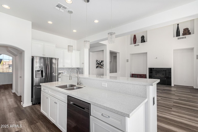 kitchen featuring dishwasher, sink, white cabinets, hanging light fixtures, and a center island with sink