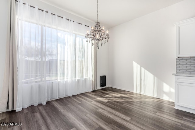 unfurnished dining area featuring a notable chandelier, dark wood-type flooring, and a wealth of natural light