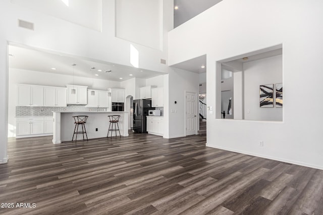 unfurnished living room featuring a towering ceiling and dark hardwood / wood-style flooring