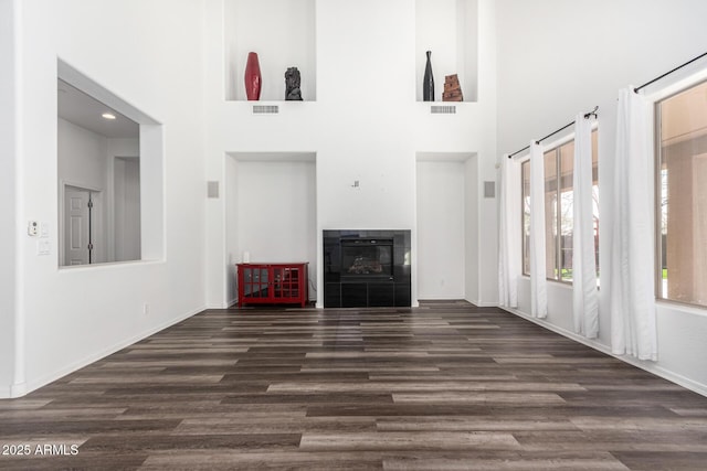 unfurnished living room with a tile fireplace, dark hardwood / wood-style floors, and a high ceiling