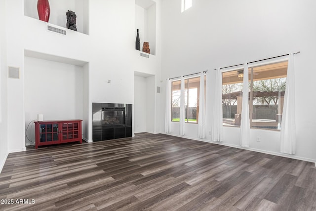 unfurnished living room with dark wood-type flooring and a tiled fireplace