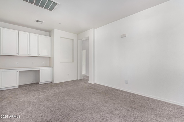 interior space featuring built in desk and light carpet