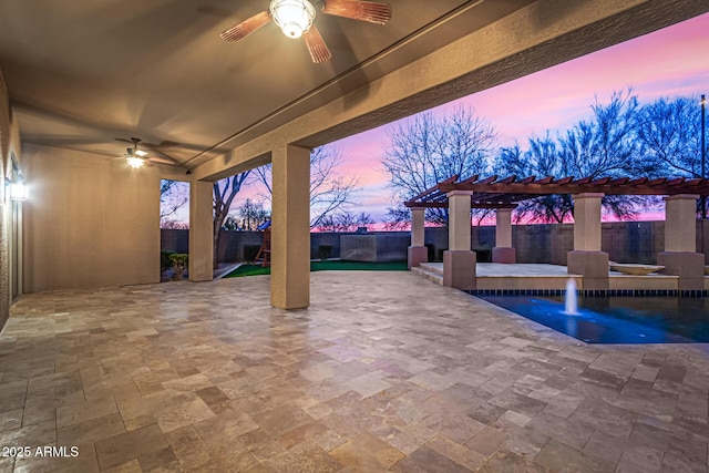 patio terrace at dusk featuring pool water feature, ceiling fan, a fenced in pool, and a pergola