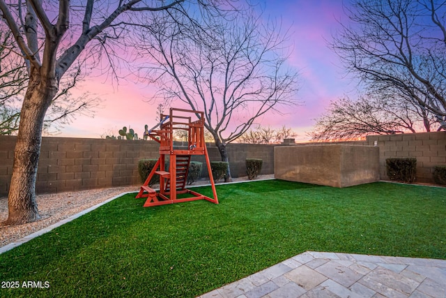 yard at dusk featuring a playground