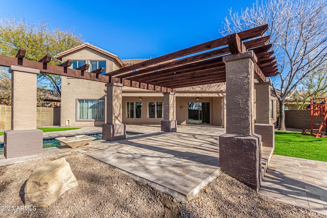 back of property with a pergola, a swimming pool, a patio area, and a playground