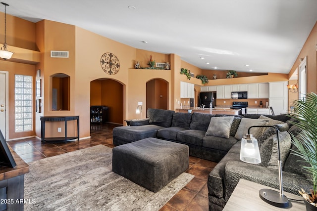 living room with dark tile patterned floors and a towering ceiling