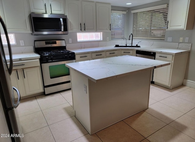 kitchen featuring a sink, light stone counters, a kitchen island, stainless steel appliances, and light tile patterned floors