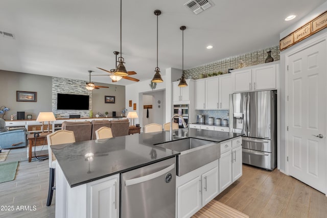 22927 E Via Del Oro, Queen Creek, AZ 85142 - kitchen with appliances with stainless steel finishes, a sink, dark countertops, a center island with sink, and a ceiling fan