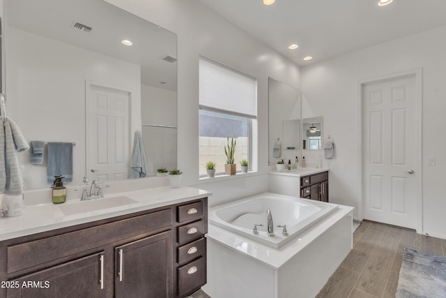 22927 E Via Del Oro, Queen Creek, AZ 85142 - bathroom featuring vanity, a garden tub, wood finished floors, and recessed lighting