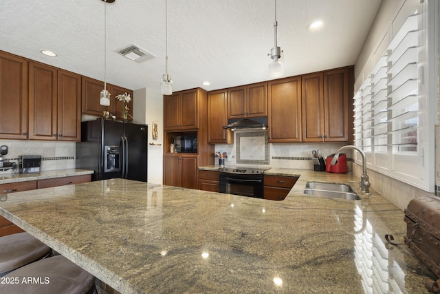 kitchen featuring visible vents, a sink, light stone countertops, under cabinet range hood, and black appliances