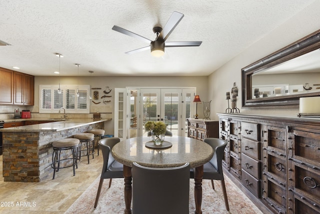 dining space featuring plenty of natural light, a ceiling fan, a textured ceiling, and french doors