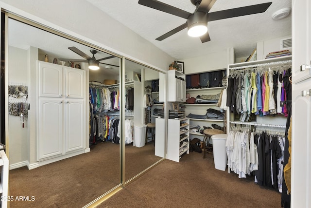 walk in closet featuring dark carpet and a ceiling fan