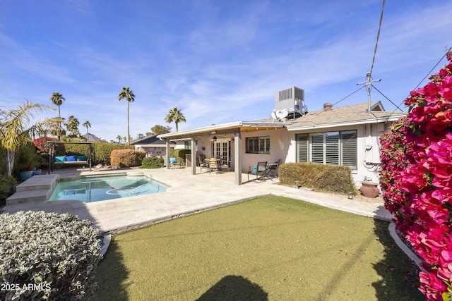 back of property featuring central air condition unit, ceiling fan, a fenced in pool, and a patio