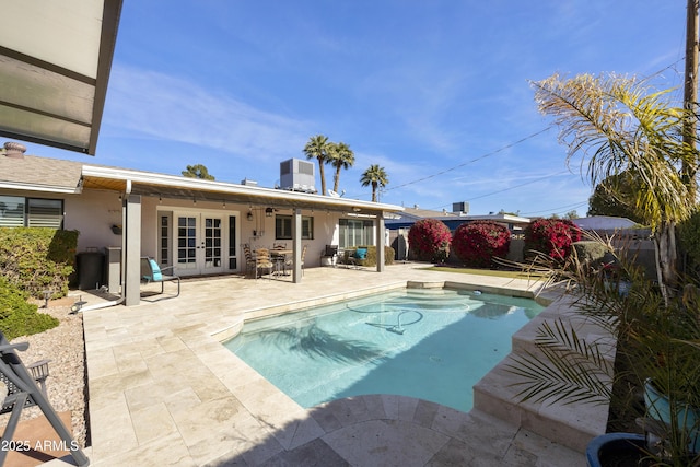 view of swimming pool featuring central air condition unit, a fenced in pool, a patio, and french doors