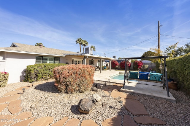 rear view of house featuring a fenced in pool, a patio, and stucco siding