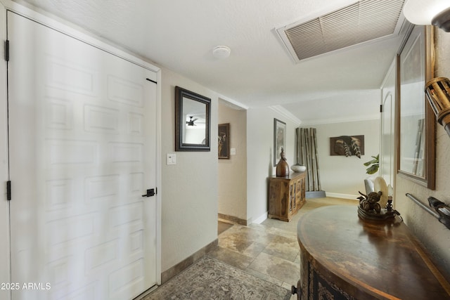 hallway featuring ornamental molding, visible vents, and baseboards