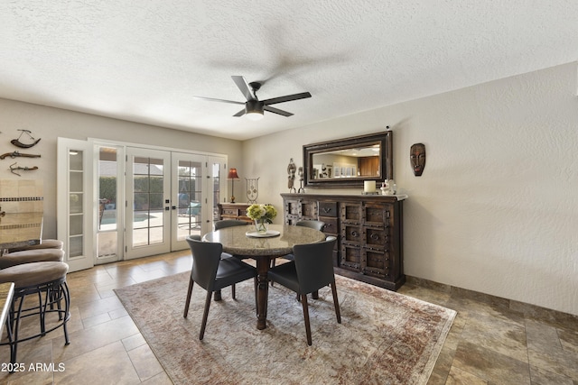 dining room featuring a textured ceiling, ceiling fan, french doors, and a textured wall