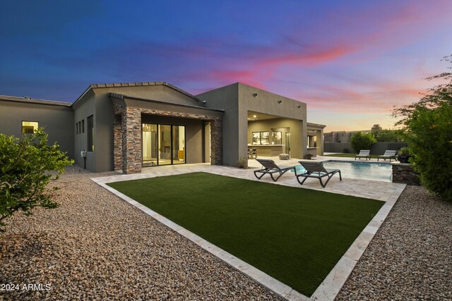 pool at dusk with a fire pit, a patio area, and pool water feature