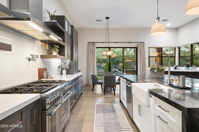 kitchen featuring extractor fan, white cabinetry, decorative light fixtures, appliances with stainless steel finishes, and a healthy amount of sunlight