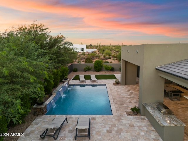 pool at dusk featuring a fire pit, pool water feature, and a patio area