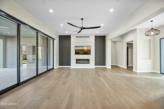 unfurnished living room featuring ceiling fan, a fireplace, and light wood-type flooring