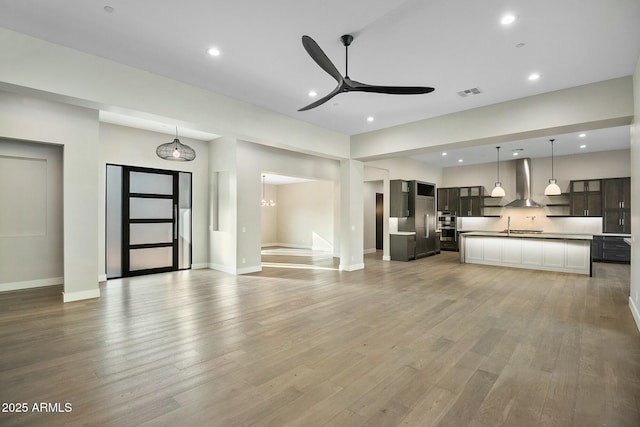 unfurnished living room featuring ceiling fan, sink, and light hardwood / wood-style flooring