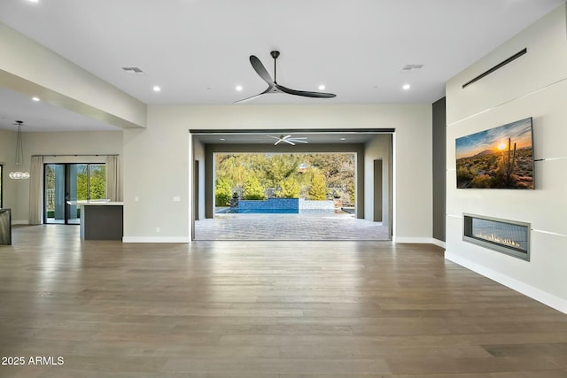 unfurnished living room featuring ceiling fan and hardwood / wood-style floors