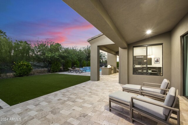 patio terrace at dusk featuring exterior kitchen, area for grilling, and ceiling fan