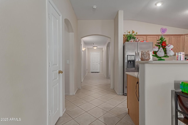 corridor featuring light tile patterned floors, vaulted ceiling, and beverage cooler