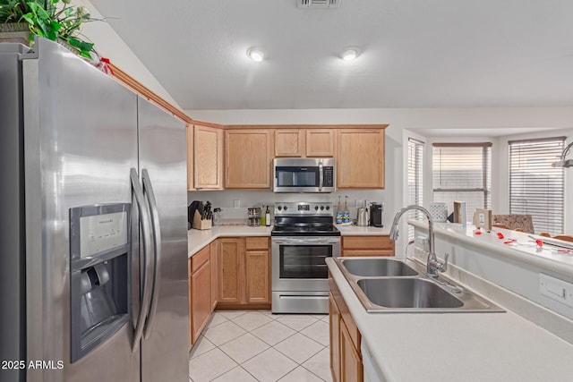 kitchen with sink, vaulted ceiling, light brown cabinets, light tile patterned floors, and appliances with stainless steel finishes