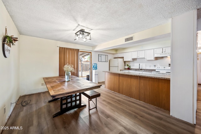 dining area with dark wood finished floors, a textured ceiling, and a chandelier