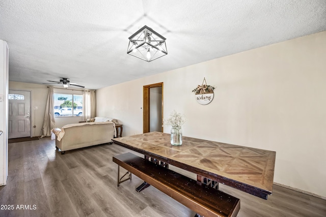 dining space with a textured ceiling, wood finished floors, a ceiling fan, and baseboards