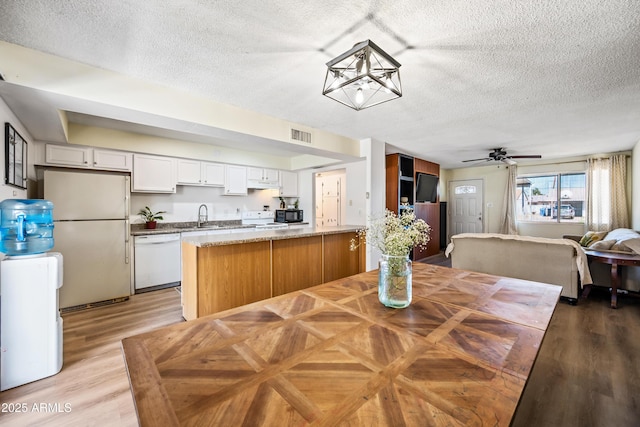 dining room with a textured ceiling, light wood-style floors, a ceiling fan, and a chandelier