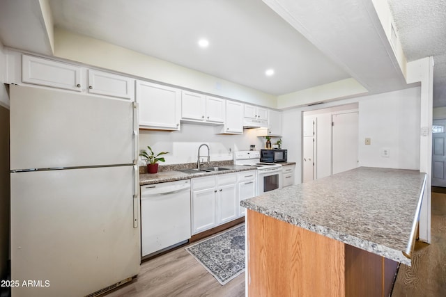kitchen with white appliances, a sink, a peninsula, white cabinets, and light wood finished floors