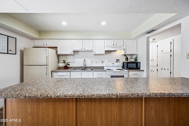 kitchen featuring white appliances, a sink, white cabinetry, under cabinet range hood, and dark countertops