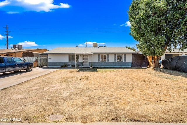 ranch-style house featuring brick siding, concrete driveway, and fence