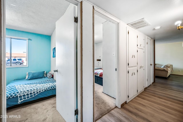 hall featuring light wood finished floors and a textured ceiling