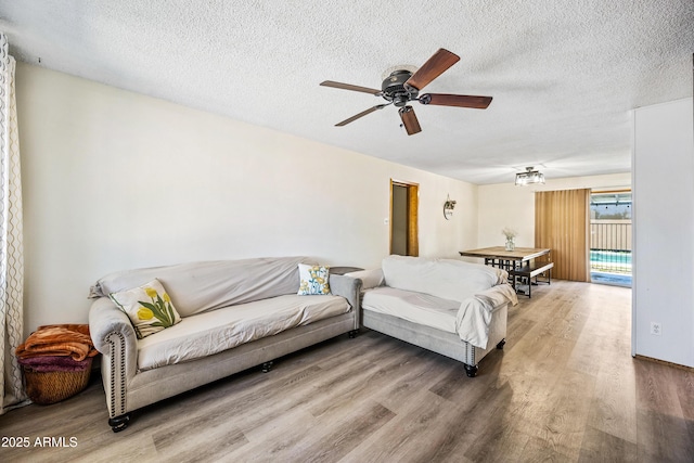 living area with wood finished floors, ceiling fan, and a textured ceiling