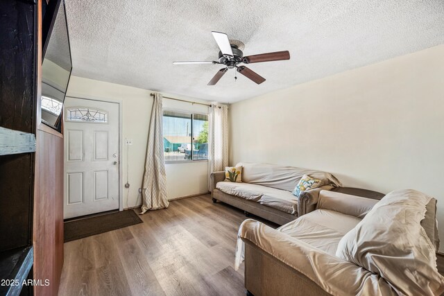 living area with wood finished floors, a textured ceiling, and ceiling fan