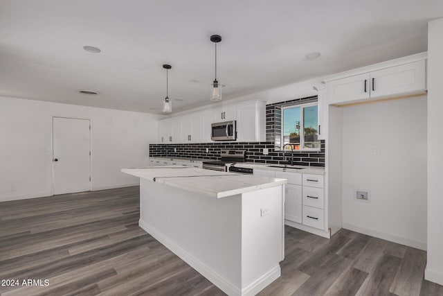 kitchen with white cabinets, a kitchen island, hanging light fixtures, and appliances with stainless steel finishes