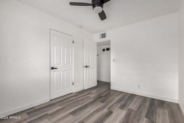 unfurnished bedroom with ceiling fan and dark wood-type flooring