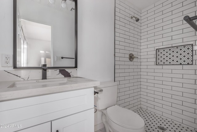 bathroom with tiled shower, vanity, and toilet