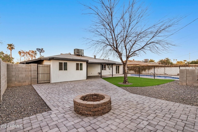 rear view of property with central air condition unit, a yard, a water view, and an outdoor fire pit