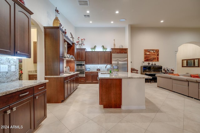 kitchen featuring decorative backsplash, a center island with sink, sink, and appliances with stainless steel finishes