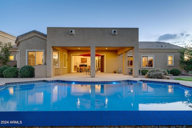 pool at dusk with a patio area